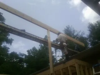 Carpenter setting a ridge beam over a new addition frame in Ossining
