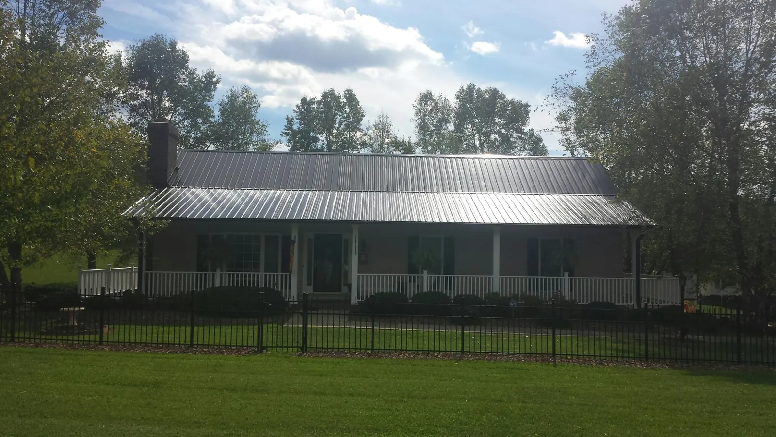 Gray metal roof on a brick ranch with a full width front porch — Gutter Guard Installation work by our crew in Ossining