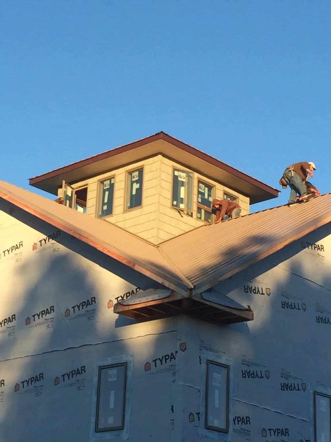 Roofers working around a rooftop cupola on a new metal roof at sunset — Roof Waterproofing in Ossining by Roofing Brothers
